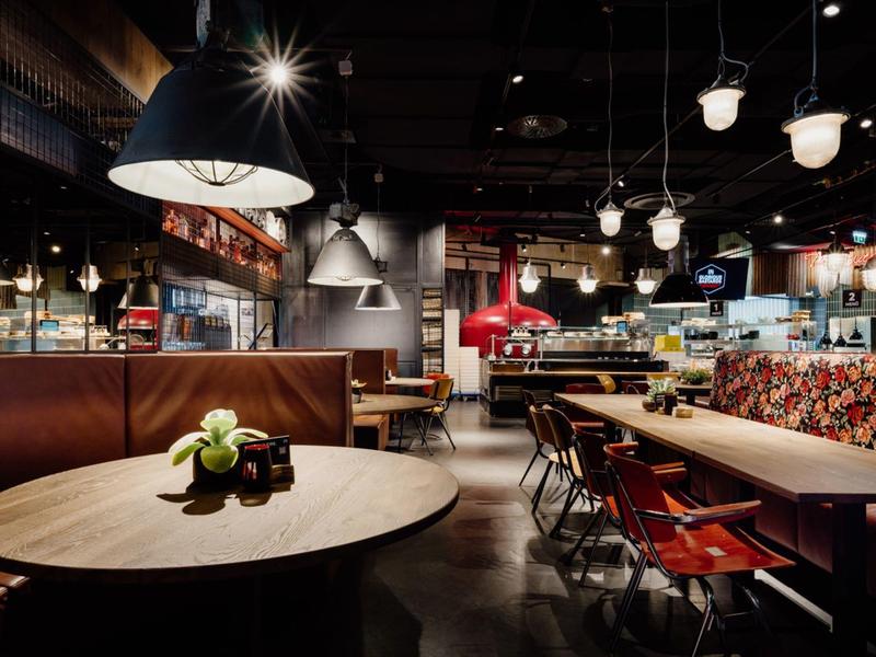 Modernes Restaurant mit runden Holztischen, Ledersesseln und warmem, gedämpftem Licht.