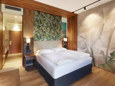 Modern eingerichtetes Hotelzimmer mit Doppelbett, Holzwänden und floralem Wanddesign.