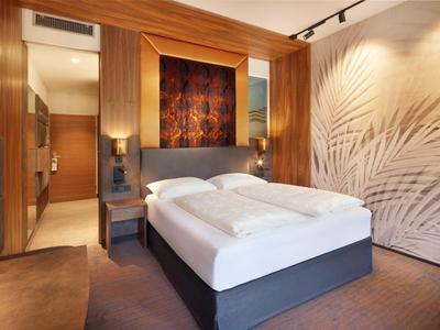 Modern eingerichtetes Hotelzimmer mit Doppelbett, Kunstwand und weicher Beleuchtung.
