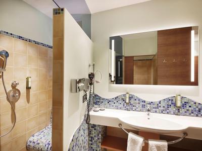 Moderner Hotelbadezimmer mit Doppelwaschbecken, beleuchtetem Spiegel und Duschkabine.