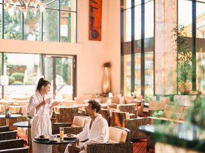 Hell beleuchtetes Hotelrestaurant mit einer Kellnerin und einem Gast im Gespräch.