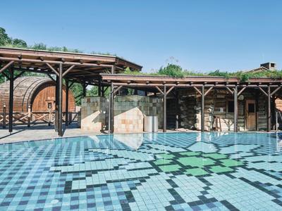 Freiluftpool mit blauem Fliesenmuster und schattigem Holzpavillon im Hotelflur.