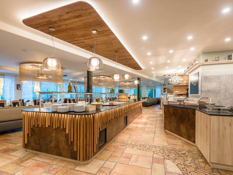 Modernes Restaurant mit Holz- und Natursteinakzenten, warmem Licht und offener Buffet-Theke.