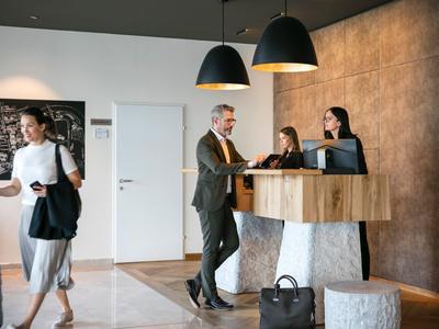 Reception dell'hotel con ospiti e personale durante il check-in in un ambiente moderno.