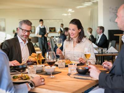 Gruppe von Erwachsenen, die in einem modernen Restaurant entspannt ein Essen genießen.