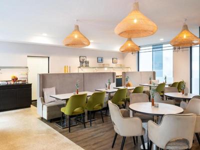 Jasna, nowoczesna restauracja z stołami, krzesłami i dużymi lampami wiszącymi