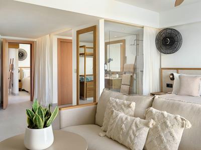 Modernes Schlafzimmer mit engen Kissen, Pflanzen in Topf und einem schwarzen Ventilator an der Wand.