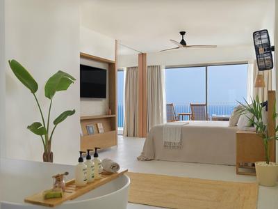 Helles Schlafzimmer mit großem Fenster, Meerblick, Pflanzen und modernem Holzdekor.