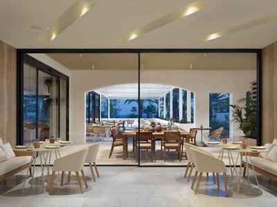 Großer, offener Wohnraum mit Sofas, Holztischen und Glaswänden, Blick auf Terrasse und Landschaft.