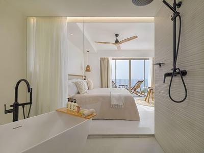 Camera moderna con vasca da bagno aperta e vista sul mare e balcone