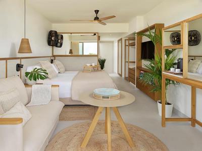 Camera d'hotel luminosa e moderna con divano, letto e mobili in legno in stile naturale.