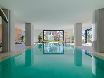 Piscina interna moderna con grandi finestre e colonne in un hotel.