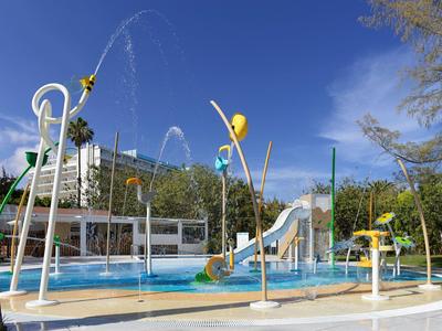 Un parco acquatico con scivoli e getti d'acqua davanti a edifici e alberi.