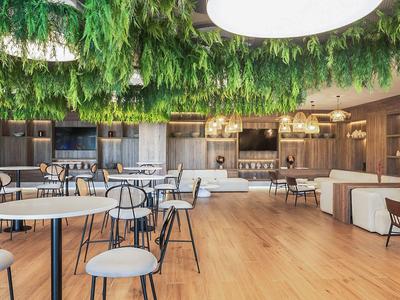 Area lounge di un hotel moderno con installazione di piante sospese e arredi minimalisti.