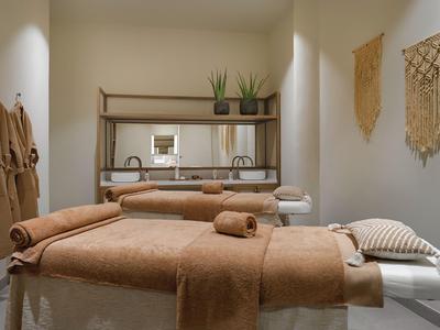 Una zona massaggi tranquilla con due lettini beige e decorazioni murali rilassanti.