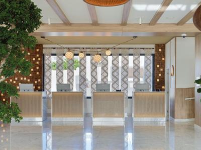 Reception di un hotel moderno con frontali in legno chiaro e lampade sospese dai colori vivaci.