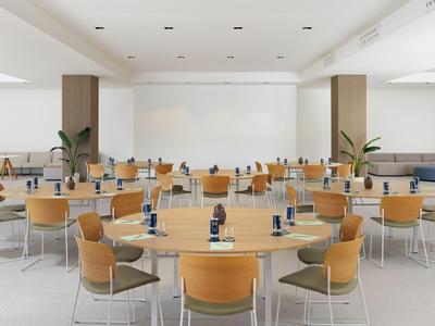 Sala conferenze moderna con tavoli rotondi e sedie marroni in un ambiente luminoso.