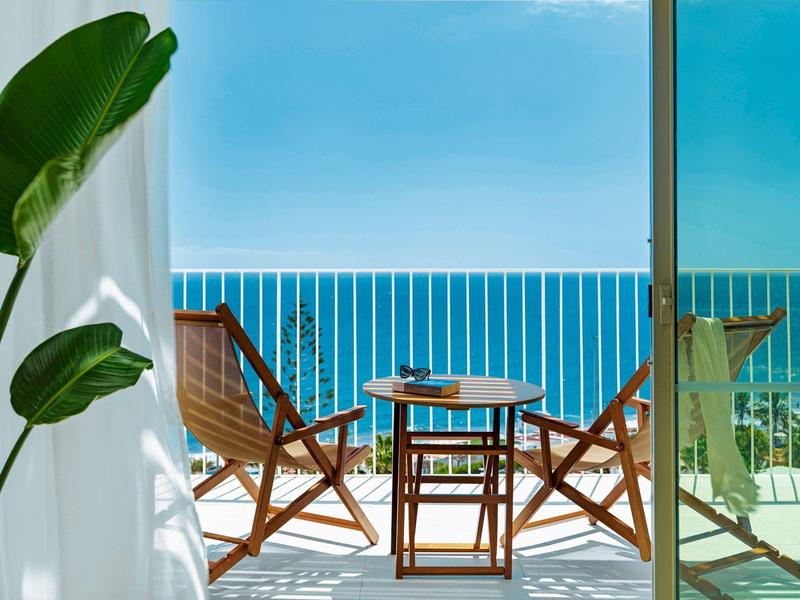 Balcone con mobili in legno che si affaccia sul mare blu in una giornata di sole