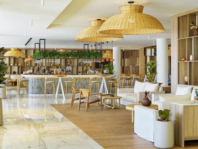 Lounge dell'hotel moderna e luminosa con bar, mobili in legno e grandi paralumi in rattan.