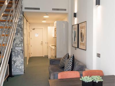 Corridoio moderno con scale, zona salotto e tavoli in una stanza d'albergo.