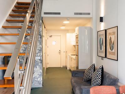 Corridoio in appartamento moderno con scala, divano, frigorifero e cuscini colorati.