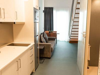 Corridoio stretto con angolo cottura moderno e vista su un soggiorno con scala.