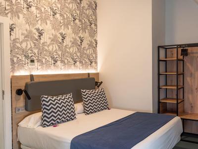 Camera d'hotel moderna con letto matrimoniale, cuscini a motivo e carta da parati elegante.