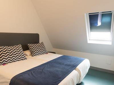 Piccola camera da letto con soffitto inclinato, letto matrimoniale e piccola finestra sul tetto.