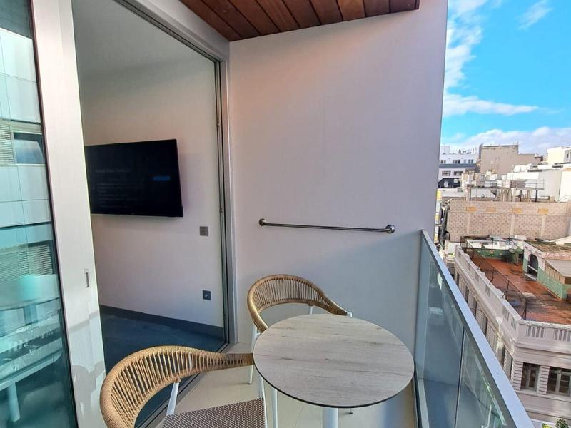 Balcone con tavolo rotondo e due sedie con vista sugli edifici circostanti.