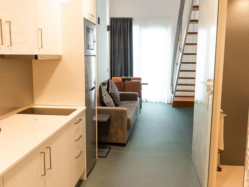 Corridoio stretto con angolo cottura moderno e vista su un soggiorno con scala.