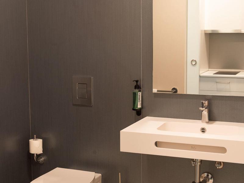 Bagno moderno con WC sospeso e lavabo rettangolare, pareti grigie.