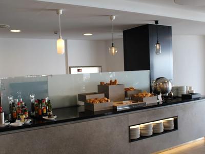 Buffetbereich mit Brot, Getränken und Gläsern in modern gestalteter, heller Raumumgebung.