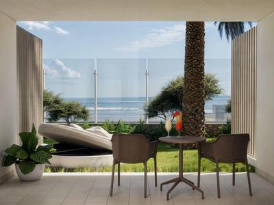 Balkon mit Glasgeländer, zwei Stühlen, Tisch und Pflanzen mit Blick auf Meer und Palmen.