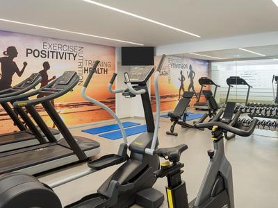 Gimnasio moderno con cintas de correr y pesas en un hotel.