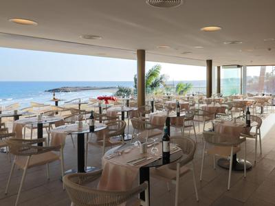 Restaurante moderno con paredes de vidrio con vistas a la playa y al mar.