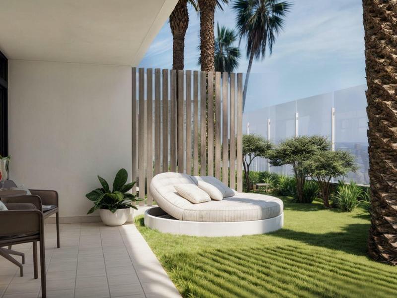 Cozy patio with chairs and round lounge bed next to palm trees and green grass.