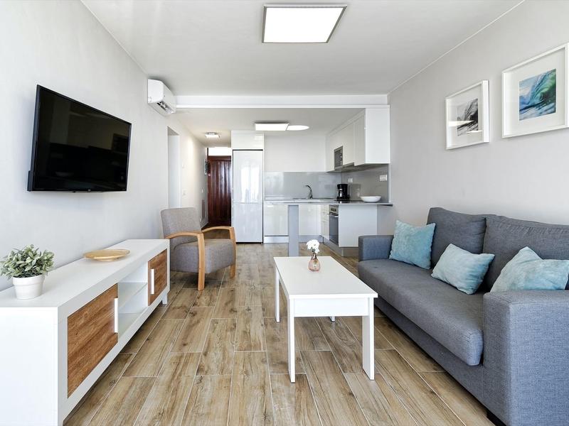 Modern living room with gray sofa, white coffee table, and wall-mounted TV.
