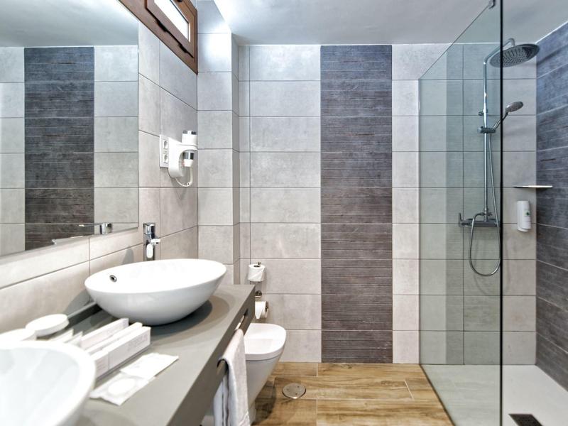 Modern bathroom with washbasin, mirror, and walk-in shower with glass partition.