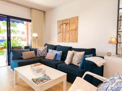 Salon confortable avec canapé bleu foncé, mobilier blanc et grande fenêtre donnant sur le jardin.