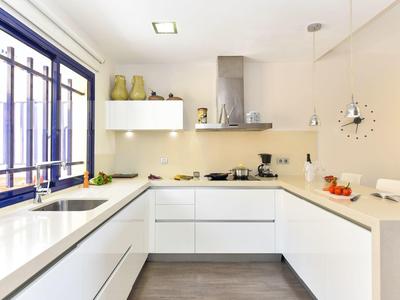 Cuisine blanche moderne avec disposition en U, fenêtre et design minimaliste.