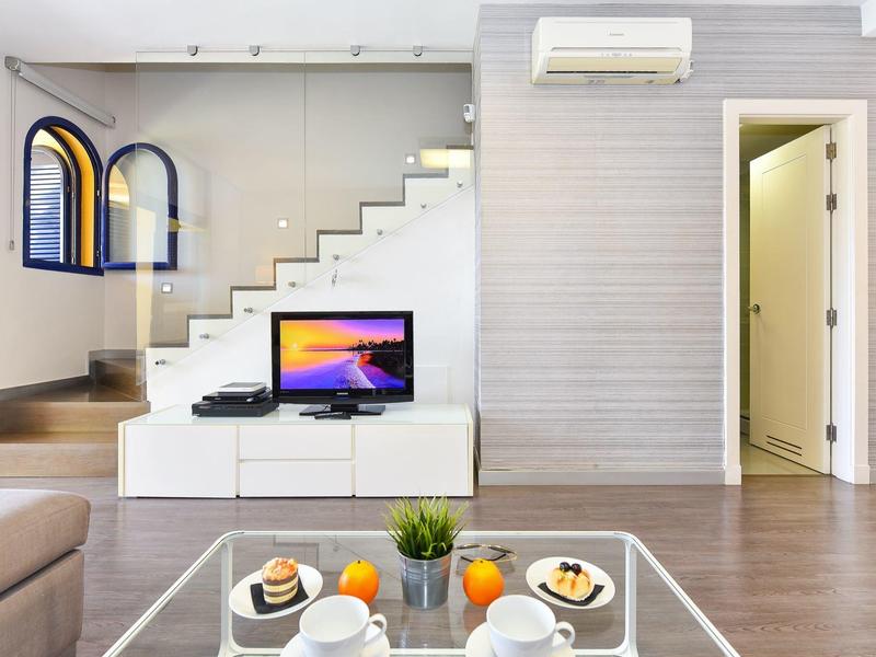 Salon moderne avec escalier, télévision et petit-déjeuner sur la table en verre.