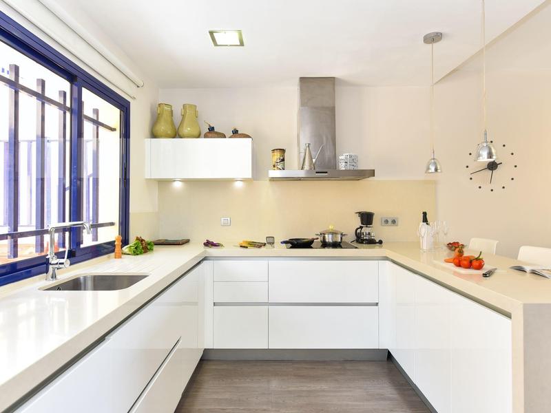 Cuisine blanche moderne avec disposition en U, fenêtre et design minimaliste.