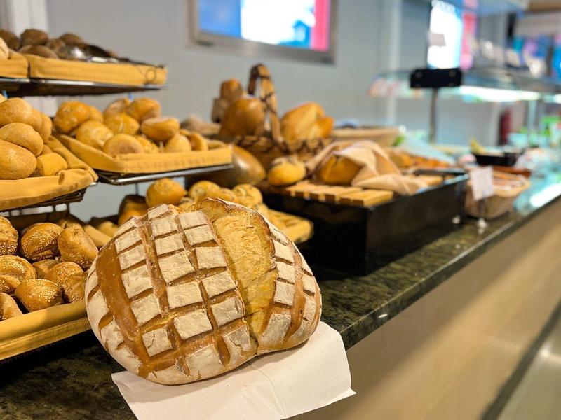 Variedad de panes frescos y bollos en una larga barra de buffet en un restaurante de hotel.