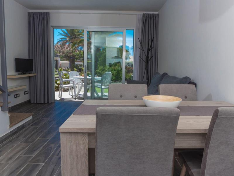 Area soggiorno moderna con tavolo da pranzo, posti a sedere e terrazza con vista sulle palme.