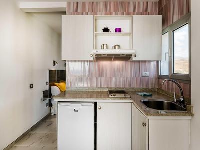 Kleine weiße Küchenzeile mit Mikrowelle, Spüle, Mini-Kühlschrank und Fenster mit Blick nach draußen.