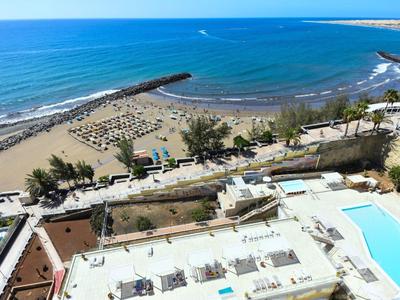 Vista di una spiaggia sabbiosa con ombrelloni e piscine accanto a un edificio dell'hotel vicino al mare
