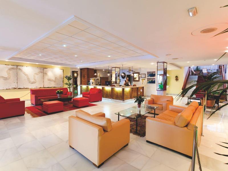 Luminosa hall d'hotel con poltrone moderne, divani e una reception sullo sfondo.