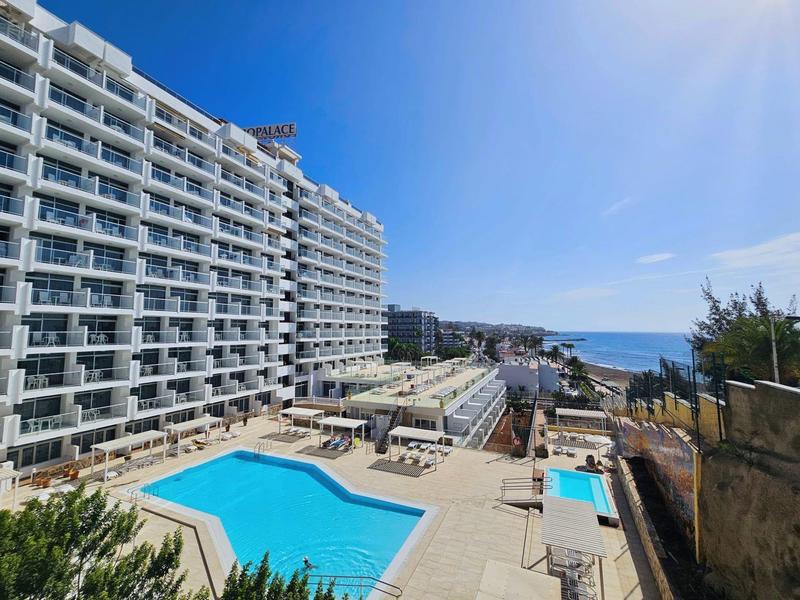 Grande edificio dell'hotel accanto a una piscina con vista sul mare in una giornata di sole.
