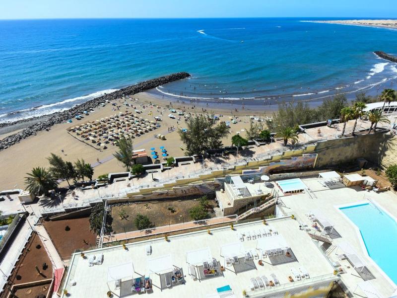 Vista di una spiaggia sabbiosa con ombrelloni e piscine accanto a un edificio dell'hotel vicino al mare