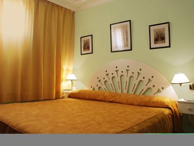 Camera d'hotel accogliente con letto grande, tende gialle e pareti verdi.